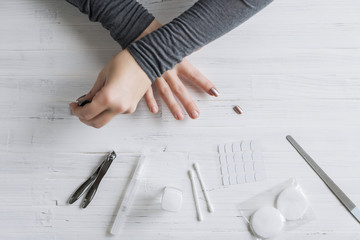 The process of putting artificial (fake) fingernail on the finger. Woman manicure. Flat lay.