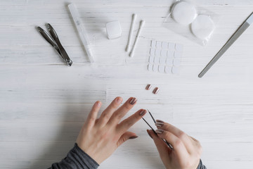 The process of putting artificial (fake) fingernail on the finger. Woman manicure. Flat lay.