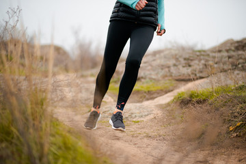 Woman Runner on the Mountain Trail at Autumn Day. Close up of Running Legs. Sport and Active Lifestyle Concept.