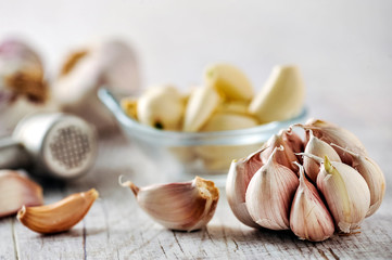 Garlic Cloves and Bulb in wooden bowl on white table.
