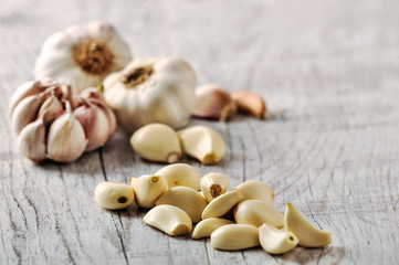Garlic Cloves and Bulb in wooden bowl on white table.
