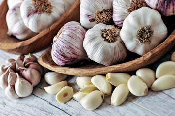 Garlic Cloves and Bulb in wooden bowl on white table.
