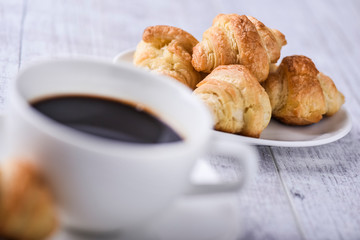 Cup of coffee on wooden tray with croissants.