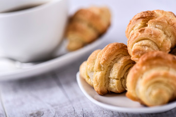 Cup of coffee on wooden tray with croissants.