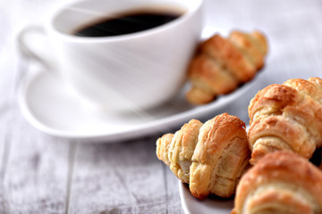 Cup of coffee on wooden tray with croissants.
