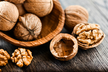 Whole walnuts on dark board, Walnut kernels in wood rustic bowl. Selective focus photo. Helathy food.