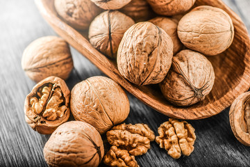 Whole walnuts on dark board, Walnut kernels in wood rustic bowl.