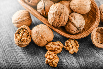 Whole walnuts on dark board, Walnut kernels in wood rustic bowl.