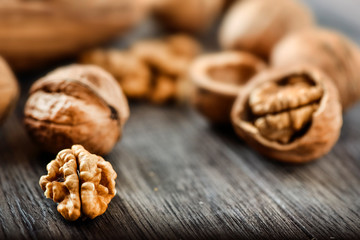 Whole walnuts on dark board, Walnut kernels in wood rustic bowl.
