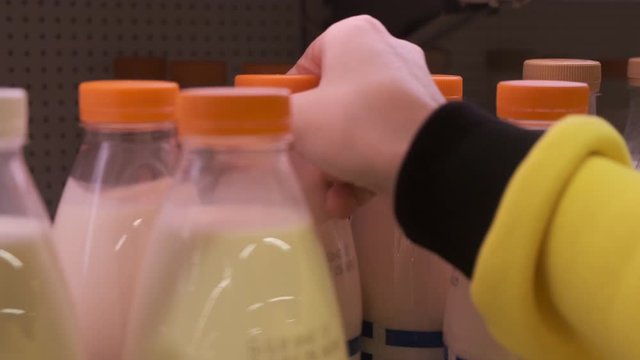 woman hand selecting milk on rack. wonam in supermarket select products from store showcase. food selection. Concept for selecting milk products in shop.