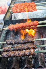 Adana kebab (ground lamb minced meat on skewer on grill over charcoal).Chef preparing traditional authentic Turkish shaworma. Middle eastern cuisine. Handmade specialty street food market with spices