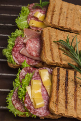 Grilled sandwiches with  salami, cheese and salad on metal grill. Outdoor food concept. .