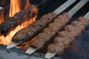 Adana kebab (ground lamb minced meat on skewer on grill over charcoal).Chef preparing traditional authentic Turkish shaworma. Middle eastern cuisine. Handmade specialty street food market with spices