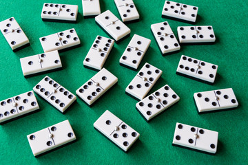 Top view of many domino pieces on green mat to play, horizontally