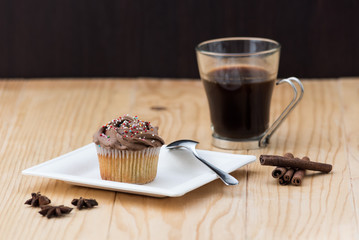 Chocolate Muffin with hot Cup of coffee, cinnamon sticks and Anise stars on a wooden table
