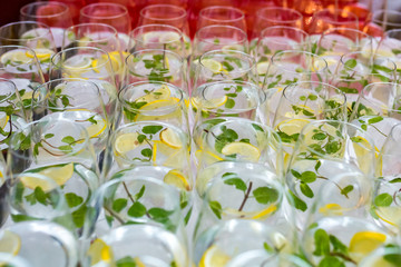 lot of blurred glasses with cocktail with lemon and mint on the reception party table