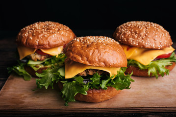 juicy homemade hamburgers with meat, cheese, lettuce, tomato on a Board