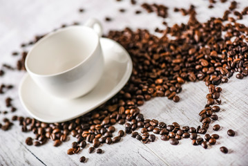 Coffee cup and beans on old white table. Roasted coffee beans top view.