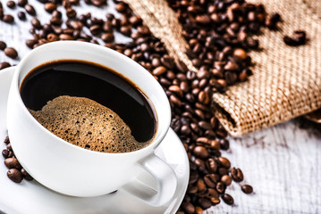 Coffee cup and beans on old white table. Roasted coffee beans top view.
