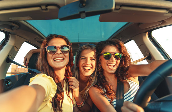 Three female friends enjoying traveling at vacation in the car.