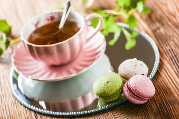 Sweet cake macarons and green tea. Colorful macarons with tea and mint on wooden table.