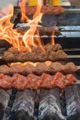 Adana kebab (ground lamb minced meat on skewer on grill over charcoal).Chef preparing traditional authentic Turkish shaworma. Middle eastern cuisine. Handmade specialty street food market with spices