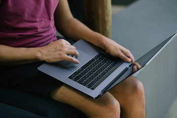 Man sitting on the floor and holding a laptop.