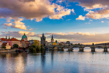 Fototapeta premium Autumn view to Charles bridge on Vltava river in Prague, Czech Republic. Autumn view to Charles Bridge, Prague old town and Vltava river. Czechia. Scenic autumn view of the Old Town with red foliage.