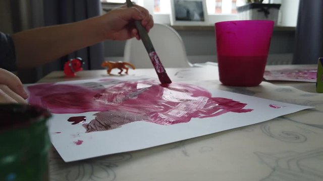 Child Artwork Creativity. Close Up of Childs Hands Painting on White Papre With Brush