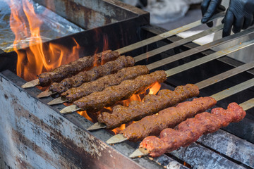 Adana kebab (ground lamb minced meat on skewer on grill over charcoal).Chef preparing traditional authentic Turkish shaworma. Middle eastern cuisine. Handmade specialty street food market with spices