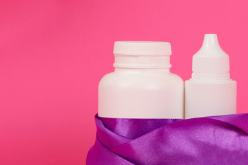 White bottles on a pink background. Gift female set. Hair Care Product. White bottle with a ribbon.