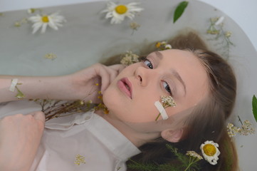 a girl in a white dress is lying in a bath with milk and flowers