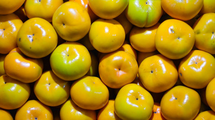 Fresh ripe persimmons placed on table in market. Organic persimmon fruit in pile at local farmers market. Persimmons background. Close-up