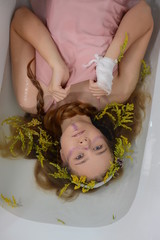 a girl in a white dress is lying in a bath with milk and flowers