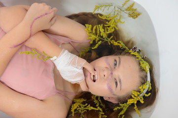 a girl in a white dress is lying in a bath with milk and flowers