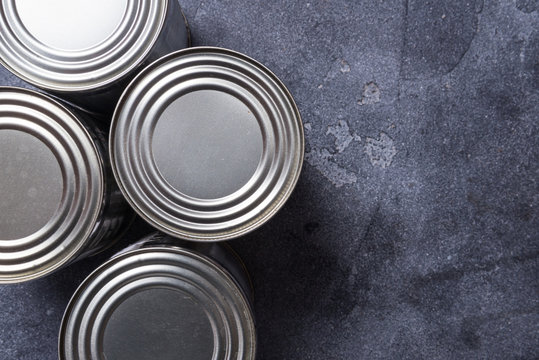 Set of metal tin cans on grey dark table, copy space