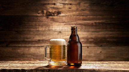 Obraz na płótnie Canvas Kufel pełen piwa i butelka na starych deskach