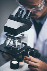 Young scientist looking through a microscope in a laboratory. Young scientist doing some research.