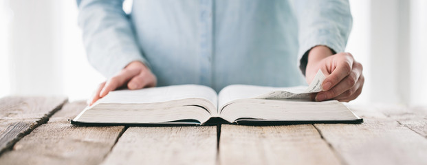 Hands turning the page of a bible. Woman reading a big book or a Bible