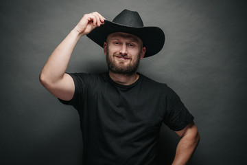 Handsome cowboy wearing black cowboy hat with beard