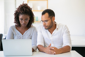 Focused employees using laptop while sitting at office. African American woman typing on laptop. Teamwork concept