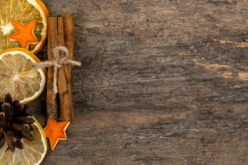 A pile of cinnamon sticks, dried orange and tangerine stars on old wooden table with copy space. Christmas decoration. Christmas card