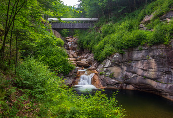 Fototapeta na wymiar Covered bridge over a cascade in New England in summer.