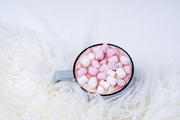 Cup of coffee with pink marshmallow on bed with warm plaid. Copy space. Flat lay, top view