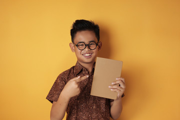 Asian student boy holding book and smiling at camera