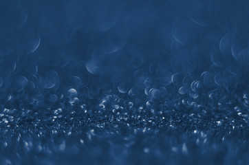 Classic Blue color. Color of the year 2020. Abstract festive bokeh background with shining defocus sparkles. Blurred glitters shimmering dust macro close up, copy space for text logo