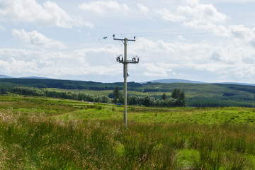 Obraz premium Strommast auf Wiesen, Felder und Hügel, bei Ledmore, in den Highlands von Schottland