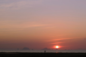 Person in the Distance Enjoying the Sunrise Over the Ocean
