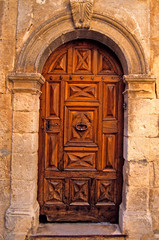 Fototapeta na wymiar An old decorated wooden door with surrounding stonework in Provence South of France