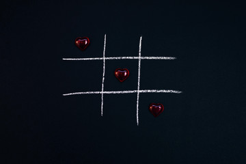 Happy Valentine's Day. 14 February. Black slate chalk Board. Souvenirs of hearts. Game TIC TAC toe.